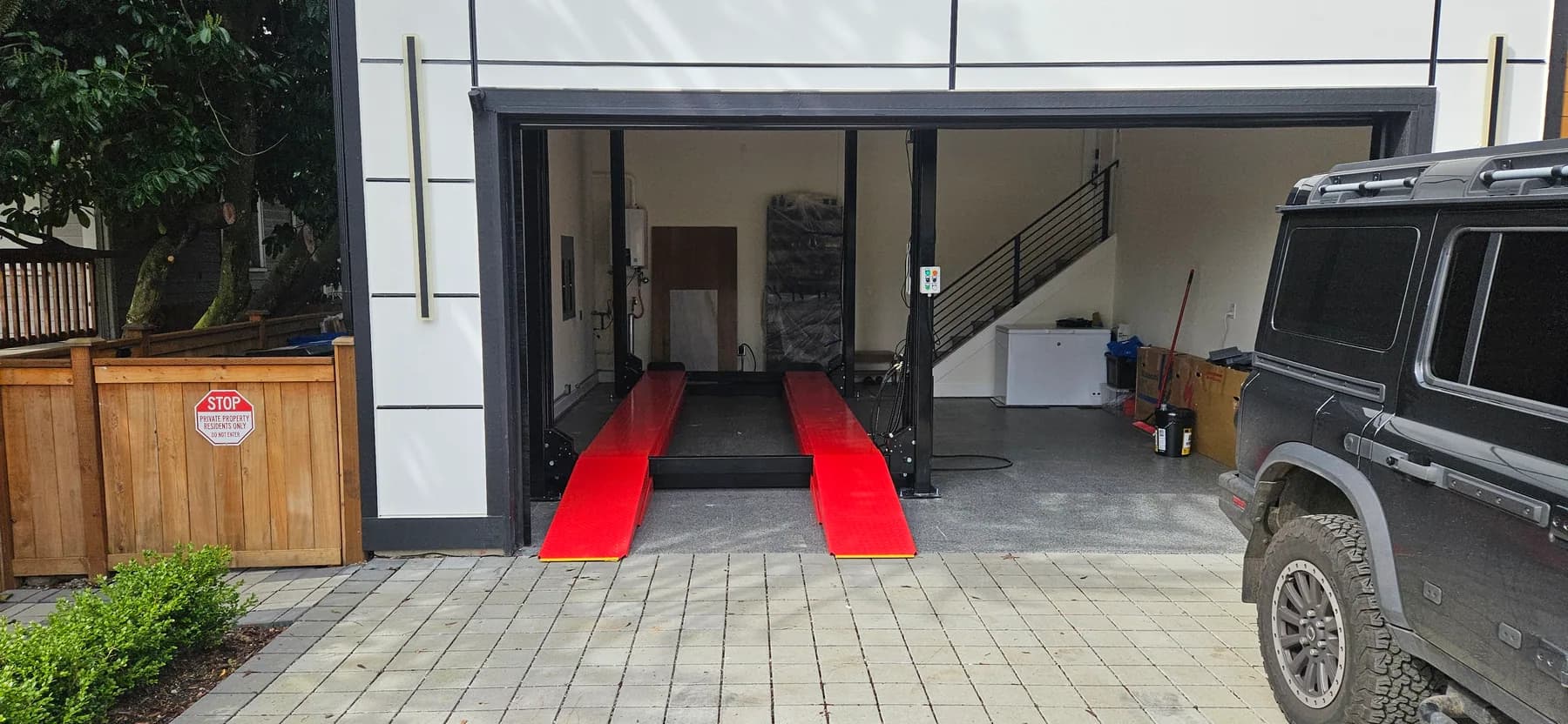 Red four-post automotive lift installed in a finished residential garage